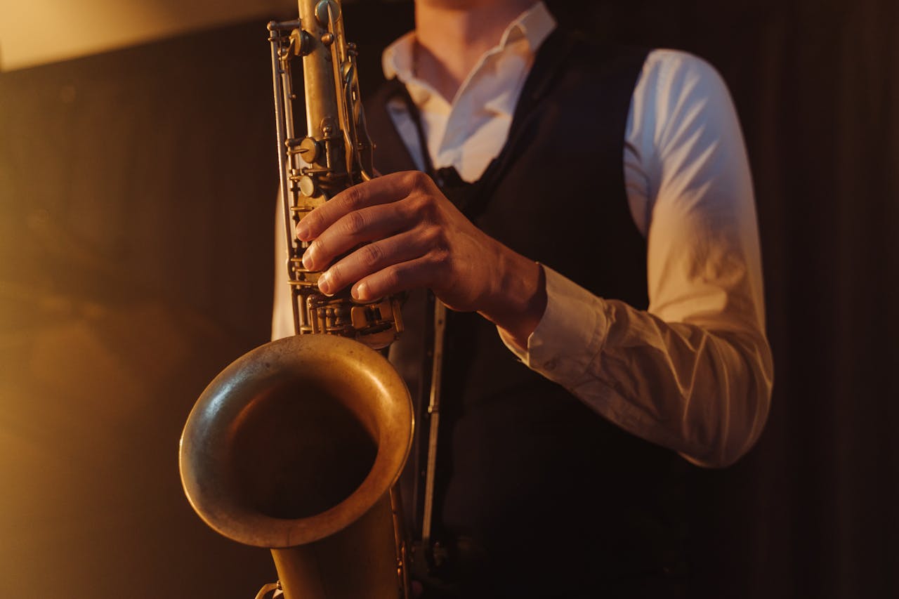 Close-up of a saxophonist playing jazz music indoors, highlighting the instrument in warm lighting.